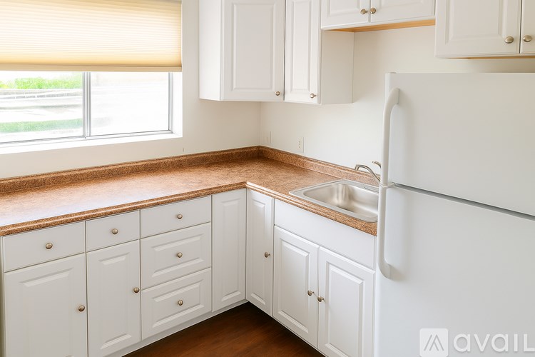 A kitchen with white cabinets and a white refrigerator.