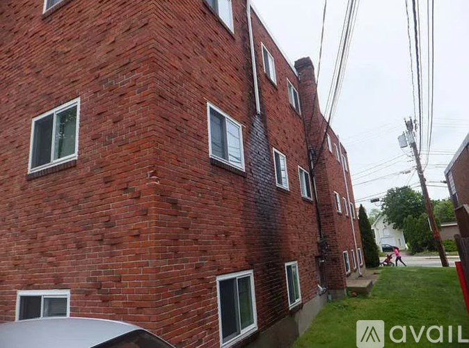 A red brick building with white windows and a sign that says "available" in the foreground.