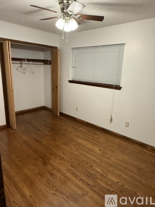A room with a ceiling fan and wooden flooring.