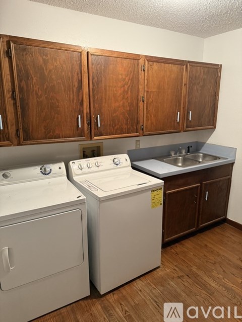 A small kitchen with wooden cabinets and a washer and dryer.