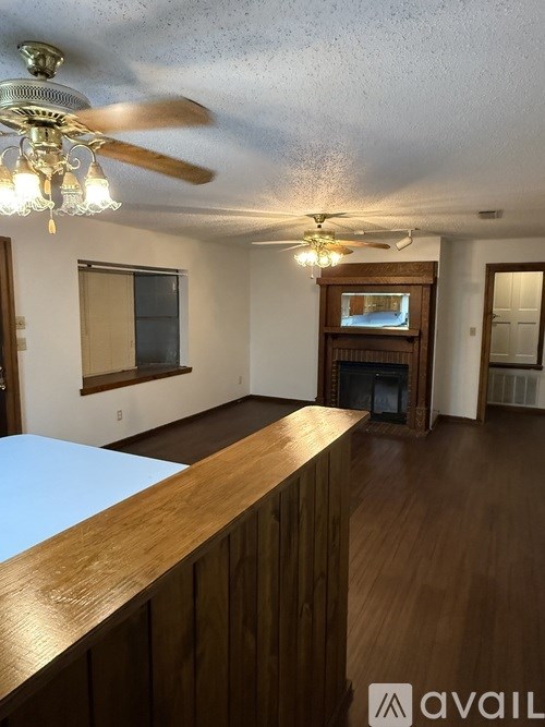 A room with a wooden floor and a ceiling fan with lights.