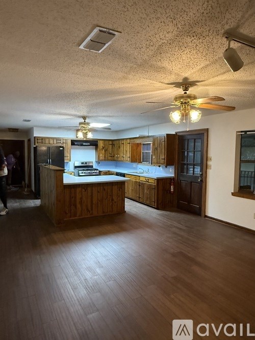 A kitchen with wooden floors and a ceiling fan.