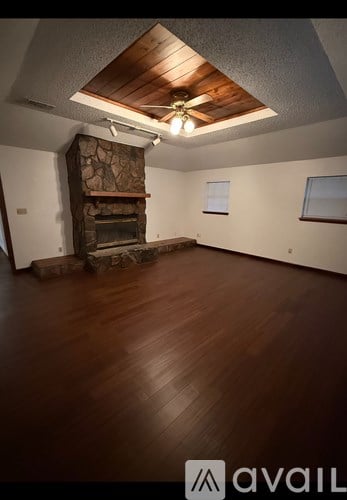 A room with wooden floors and a stone fireplace.