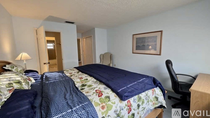 A bedroom with a bed, chair, and a painting on the wall.