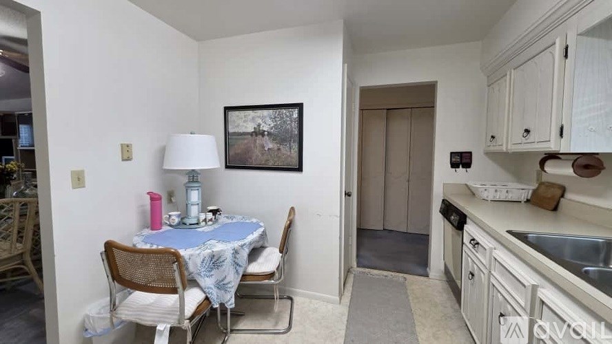 A kitchen with a table and chairs in the foreground and a sink in the background.
