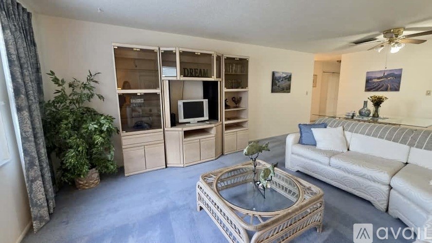 A living room with a white couch, a coffee table, and a television.