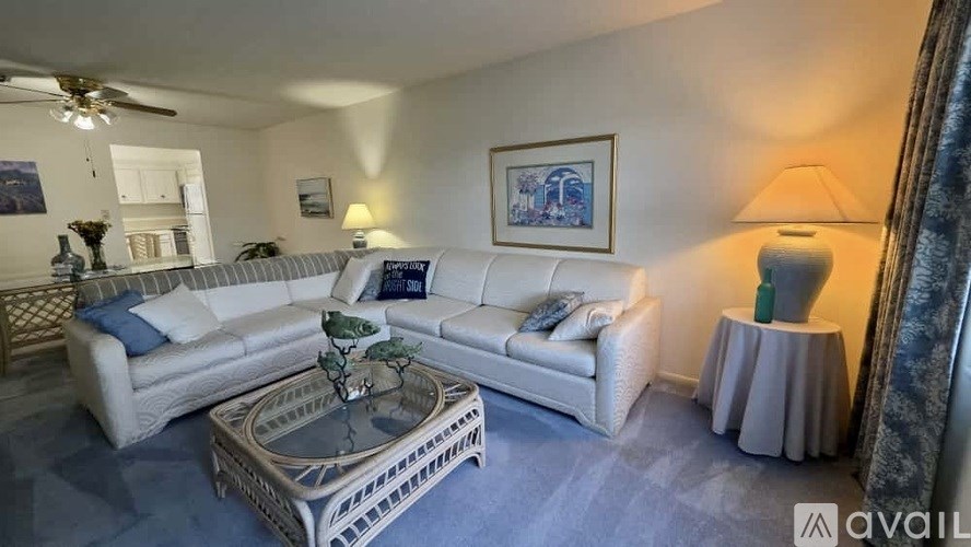 A living room with a white sofa and a glass coffee table.