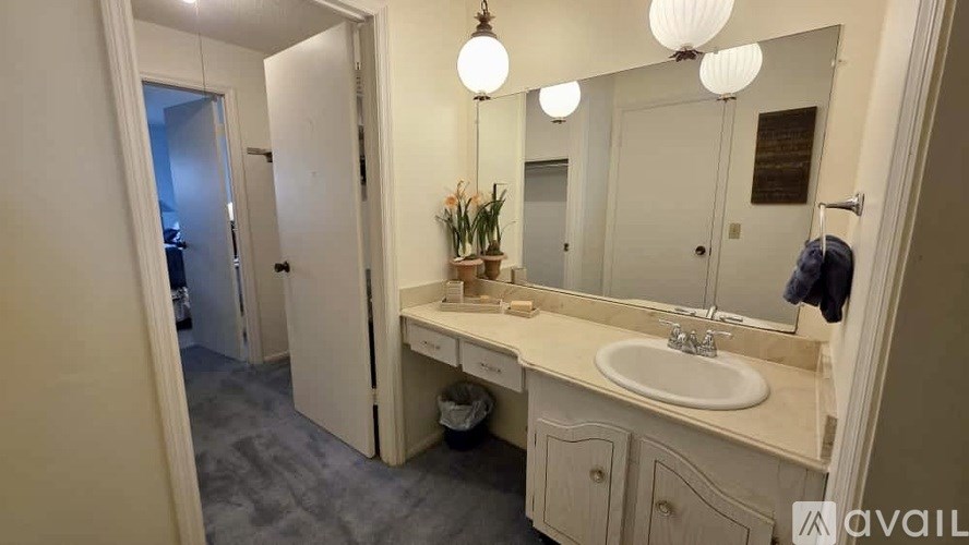 A bathroom with a sink, mirror, and a door.
