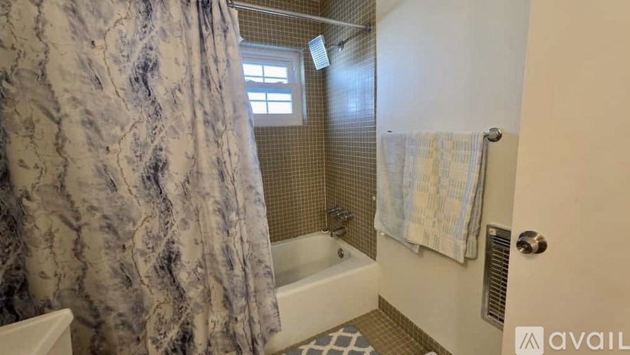 A bathroom with a shower curtain and a towel hanging on the door.