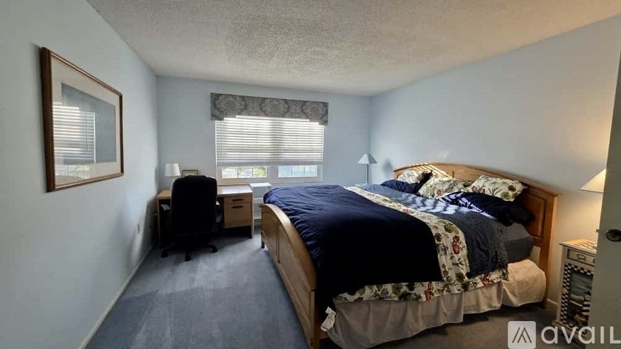 A bedroom with a bed, desk, and chair.