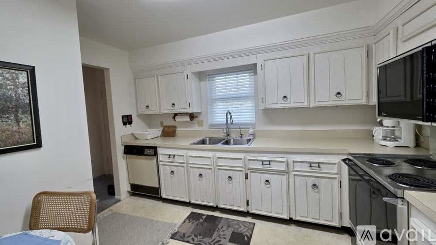 A kitchen with white cabinets and appliances.