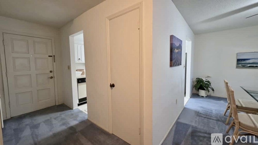 A room with a door, a chair, and a painting on the wall.