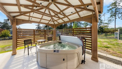 A hot tub is surrounded by a wooden deck and a pergola.
