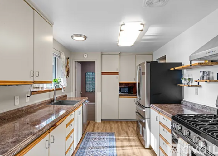 A kitchen with a black refrigerator and a black stove top oven.