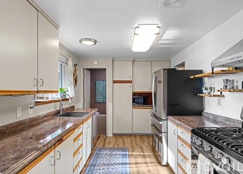 A kitchen with a black refrigerator and a black stove top oven.
