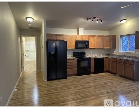 A kitchen with wooden floors and black appliances.