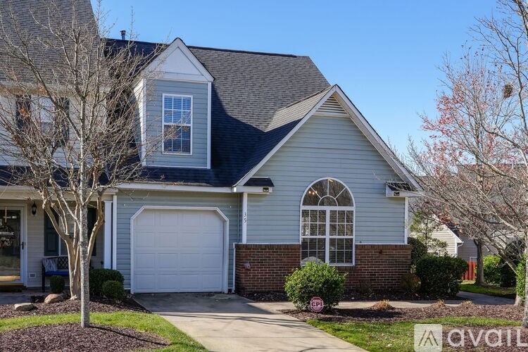 A house with a garage and a tree in front.