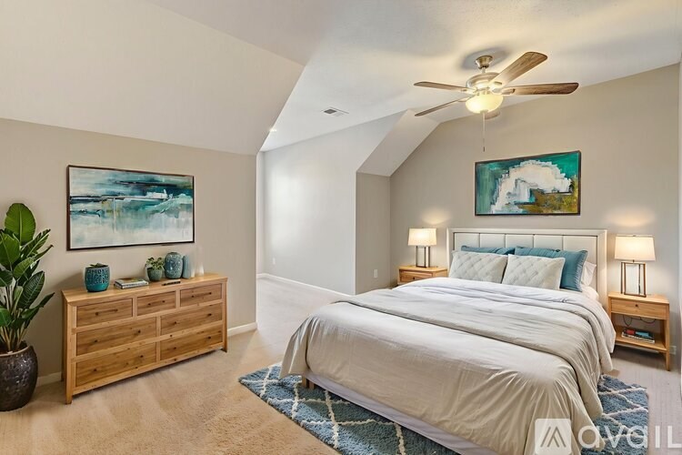 A bedroom with a large bed, a wooden dresser, and a ceiling fan.