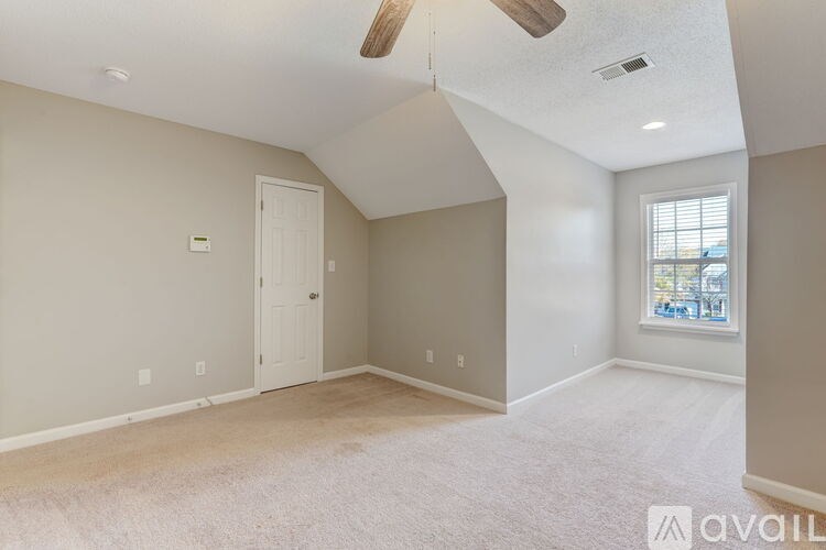 A room with a carpeted floor and a window showing a street view.