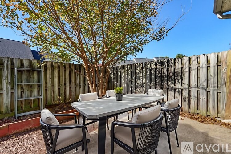 A table with chairs is set up outside with a tree in the background.