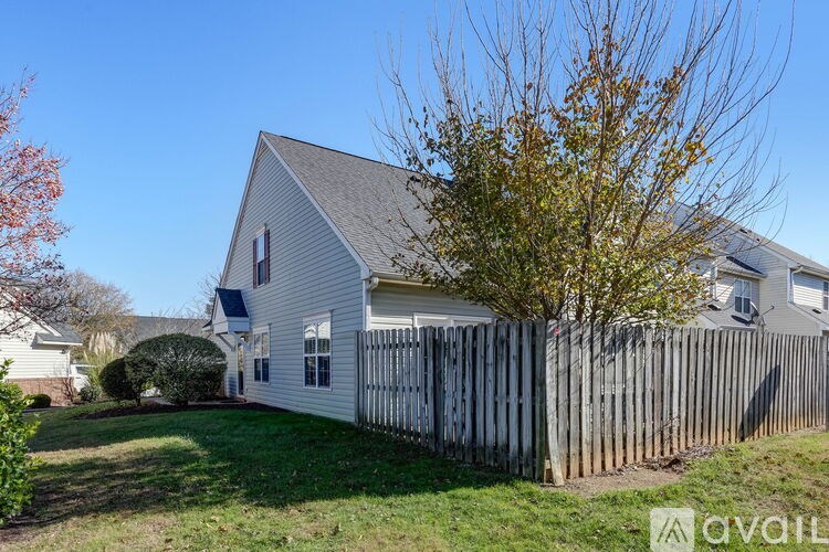 A house with a white picket fence and a tree in front.