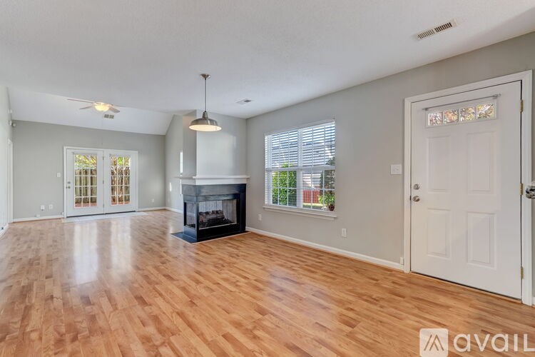 A spacious room with wooden floors and a fireplace.