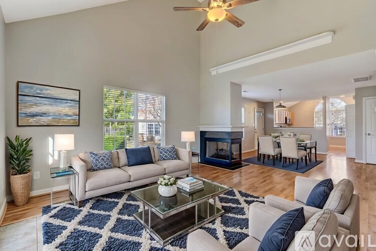 A living room with a beige couch, a glass coffee table, and a painting on the wall.