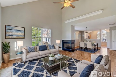 A living room with a beige couch, a glass coffee table, and a painting on the wall.