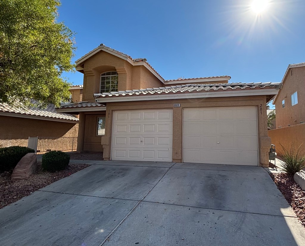 A house with a tan garage door and a brown roof.
