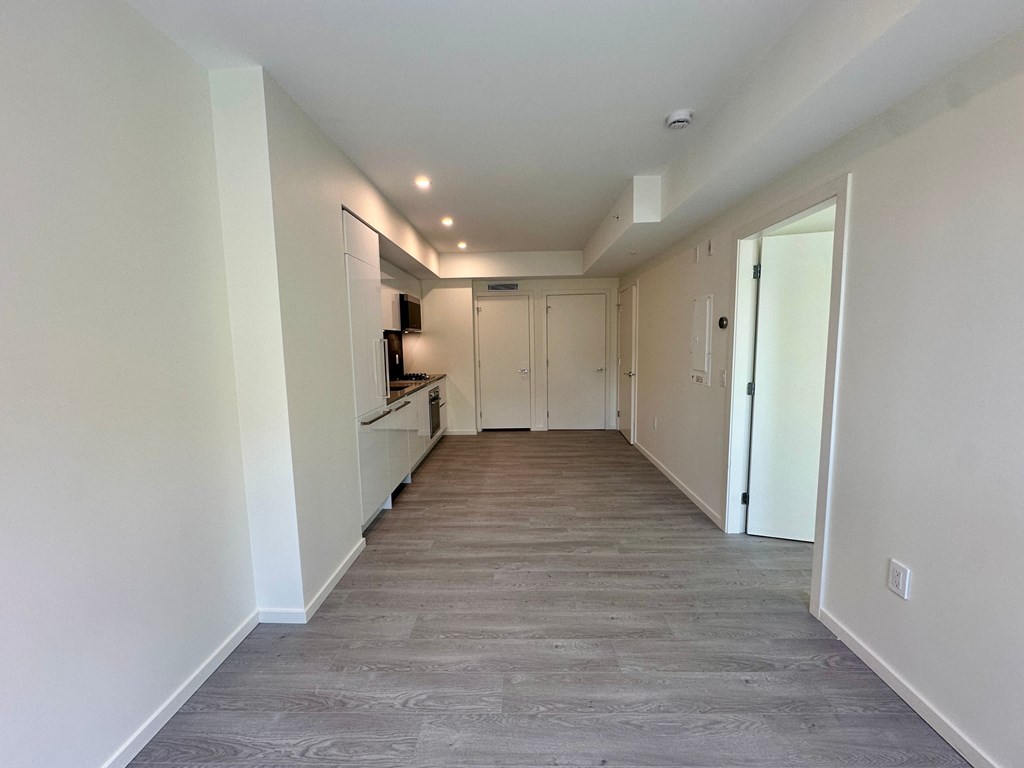 A long, empty hallway with a television on the wall.