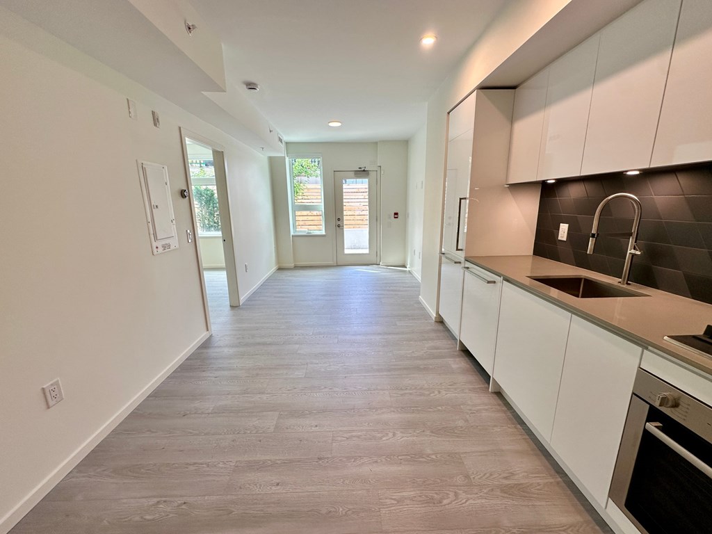 A kitchen with white cabinets and a grey floor.