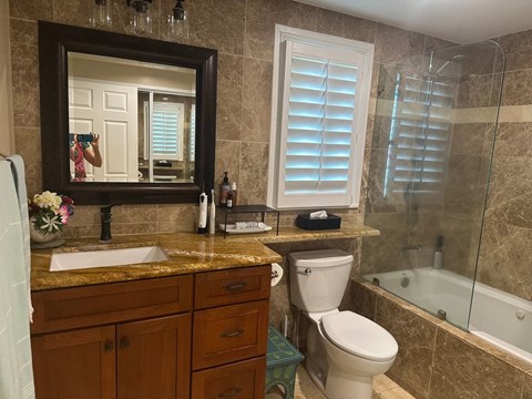 A bathroom with a sink, mirror, toilet, and bathtub.