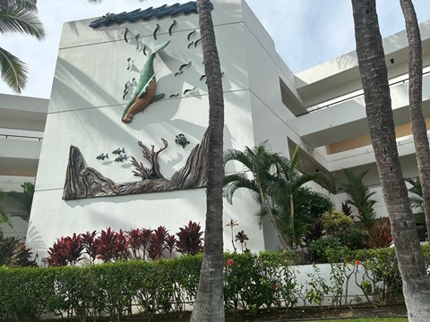 A white building with a mural of a fish and trees.