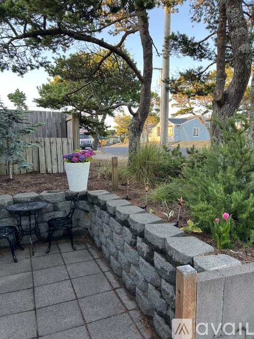 A patio with a stone wall and a table with chairs.