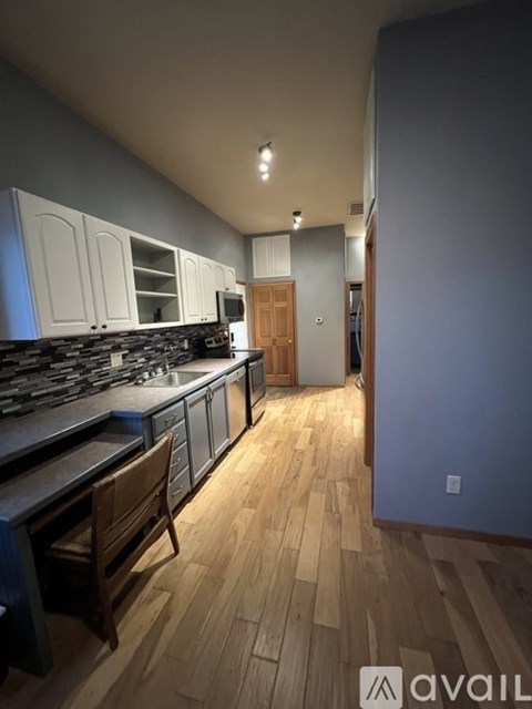 A kitchen with wooden floors and a dark counter top.