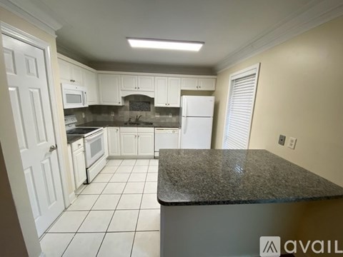 A kitchen with white cabinets and a granite countertop.