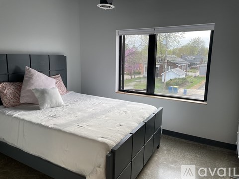 A bedroom with a large bed and a window overlooking a residential area.
