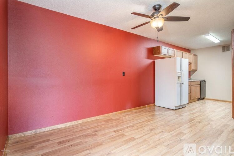 A room with a ceiling fan and a white refrigerator.
