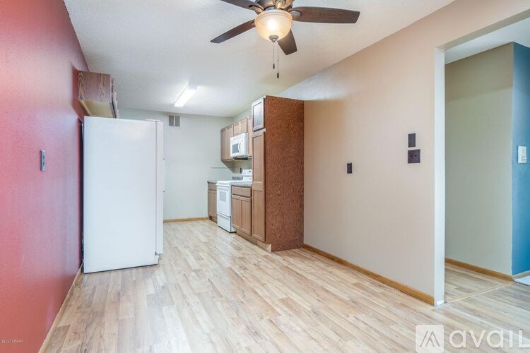 A room with a white fridge and a ceiling fan.