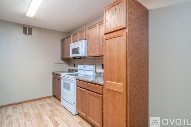 A kitchen with wooden cabinets and a white microwave.
