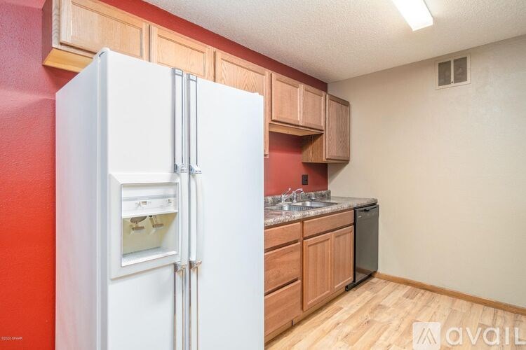A kitchen with a white refrigerator and wooden cabinets.