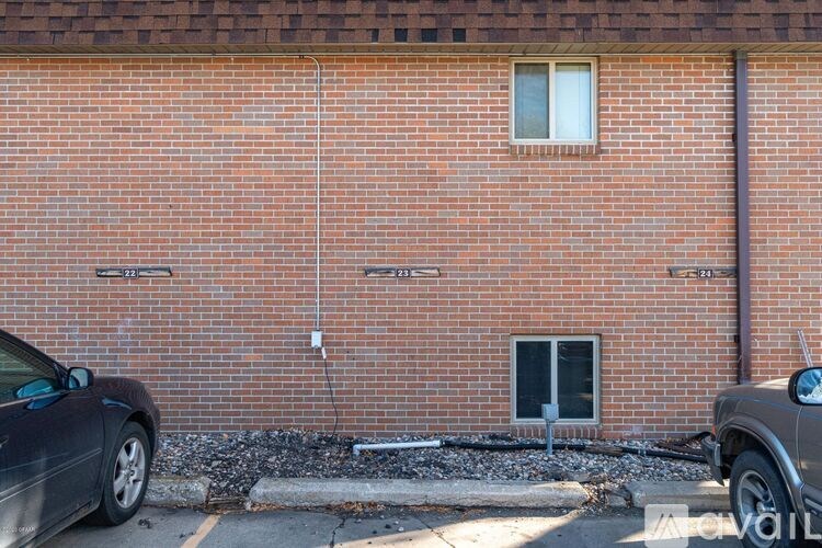 A black car is parked in front of a red brick building.