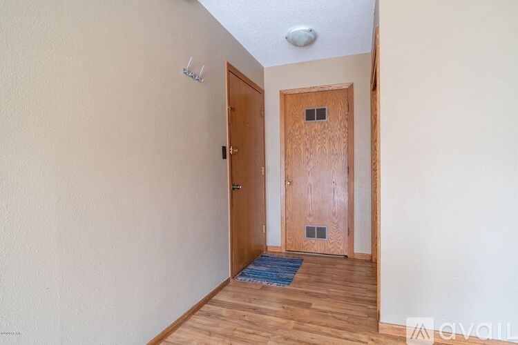 A room with a wooden door and a blue rug on the floor.