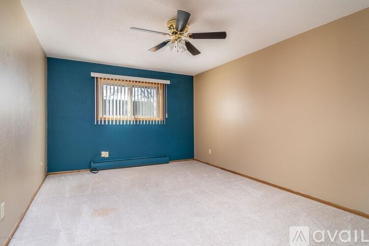 A room with a ceiling fan and a window with blinds.