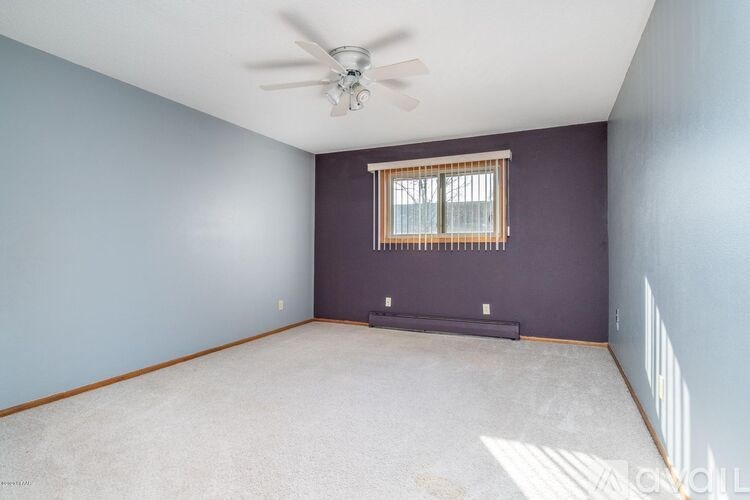 A room with a ceiling fan and a window with blinds.