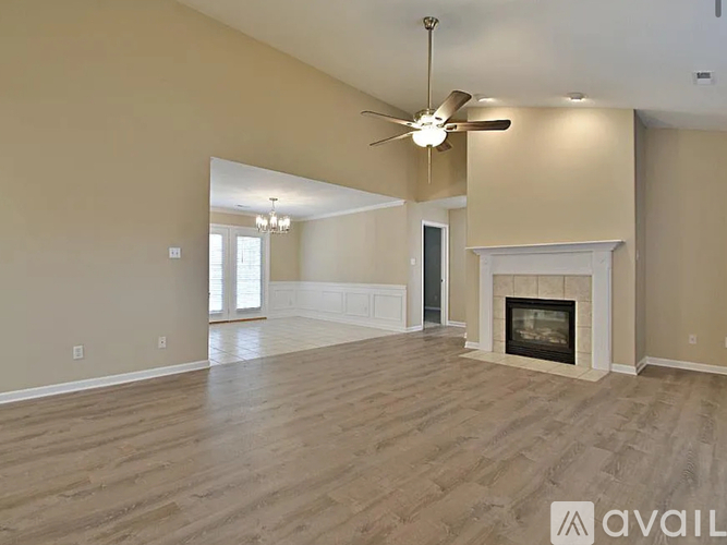 A spacious living room with a fireplace and a ceiling fan.