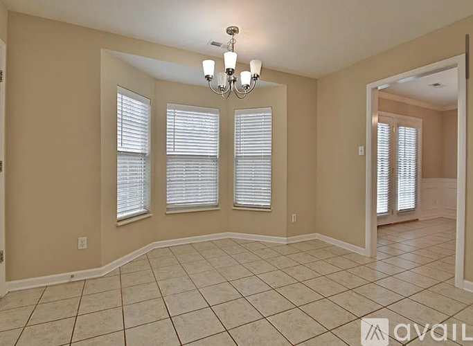 A room with beige walls, a chandelier, and a tiled floor.