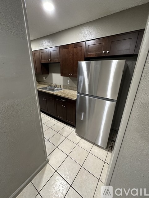 A kitchen with a stainless steel refrigerator and brown cabinets.