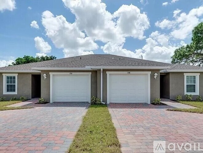A house with a grey roof and two white garage doors.