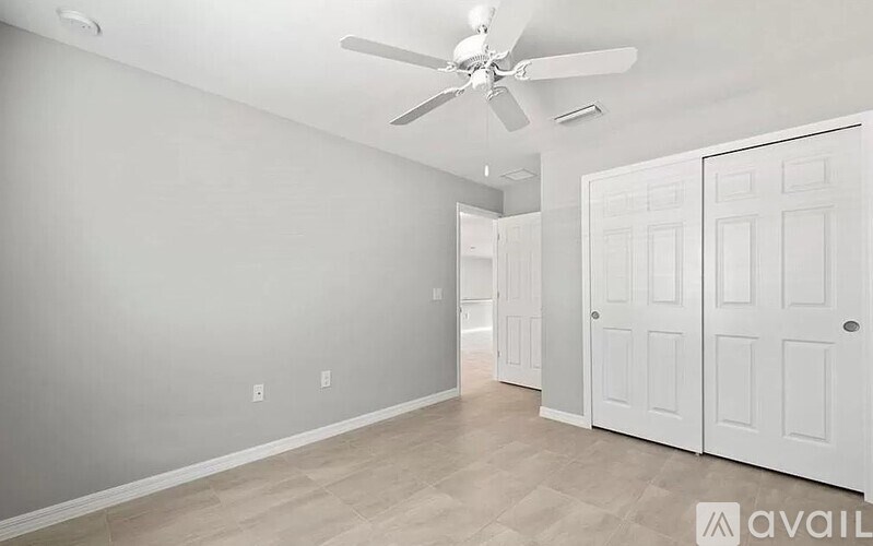 A room with a ceiling fan and a door.